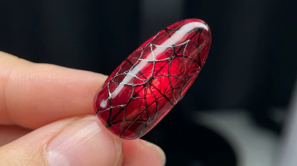 solid glossy red nail next to webbed red spiderweb nail