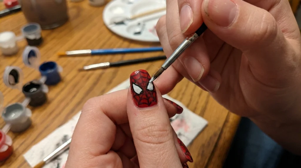 painting an original spooky eye accent on red spiderweb nails