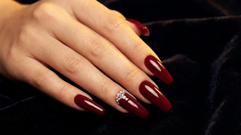 vampy red acrylic nails with rhinestone cluster accent.